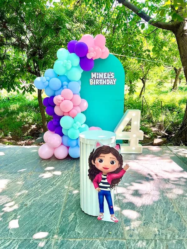 دکور تولد با تم Gabby's Dollhouse - خانه عروسکی گبی، شامل بادکنک رنگارنگ، بکگراند فیروزهای، عدد ۴ نورانی و استند شخصیت گبی"