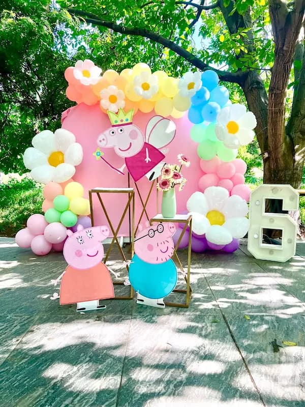 دکور تولد با تم Peppa Pig با بادکنک گلدار، بکگراند صورتی و استند شخصیتهای پپا و daddy pig"