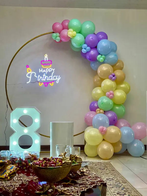 دکوراسیون تولد مینیمال رنگارنگ با بادکنک های زنگی روی حلقه طلایی، تابلوی نئونی Happy Birthday، عدد نورانی ۸